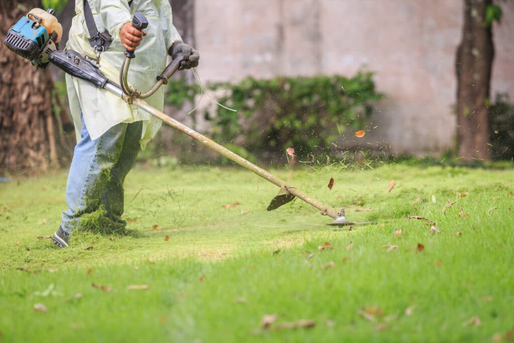 A man mowing the grass with portable machine in the garden