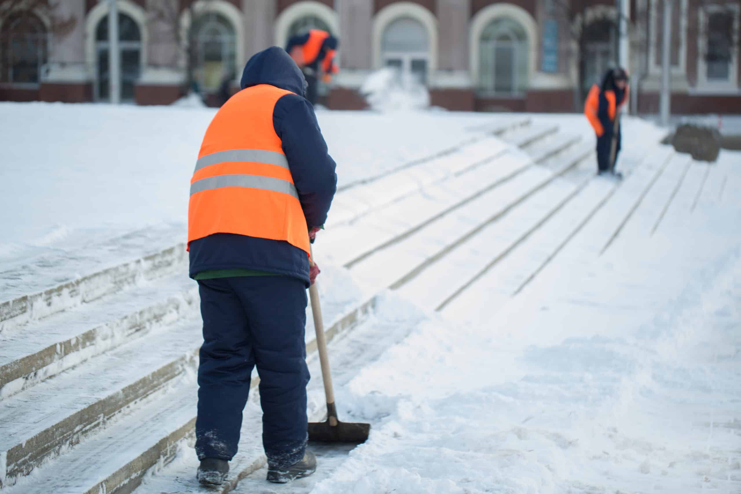 Workers sweep snow from road in winter, Cleaning road from snow storm.